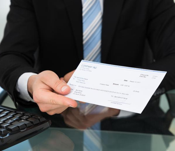 well suited man with a blue tie holding a check on his hand