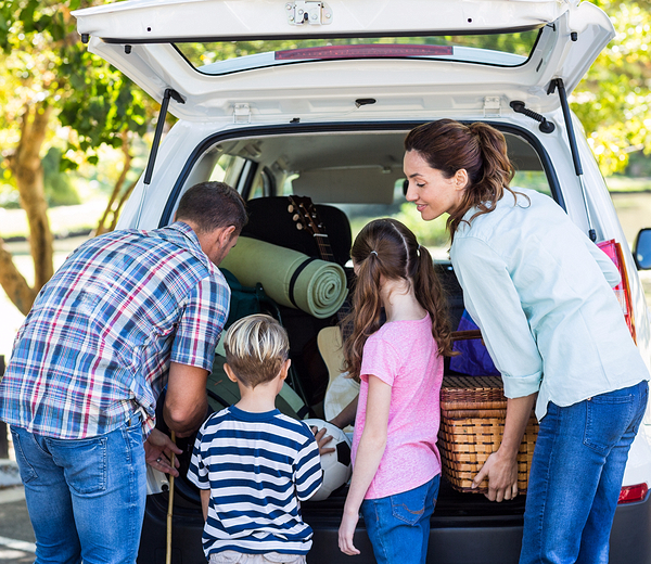 a family two kids and mom dad filling stuff in the car for a trip