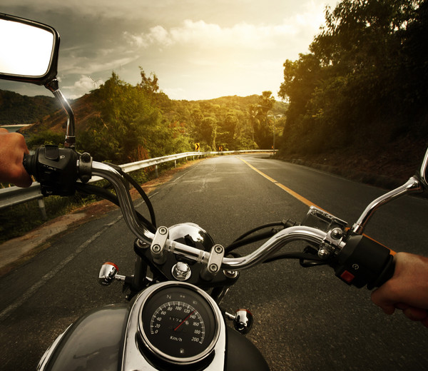 man riding a motorcycle with a great view and empty road.